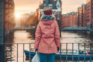 Back view of a woman with a view of the historic warehouse district in Hamburg in the warm light of sunset, Germany, Europe, Back view of a woman with a view of the historic warehouse district in Hamburg in the warm light of sunset, Germany, Europe,
